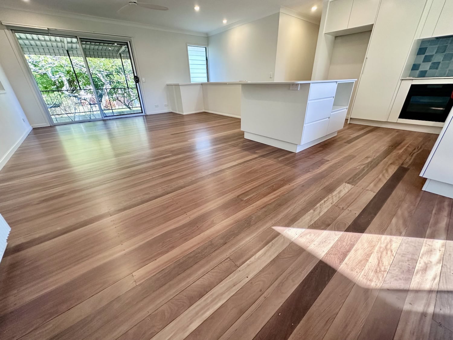 Modern hardwood flooring in an open kitchen and living space — example finish for Wilston timber floors