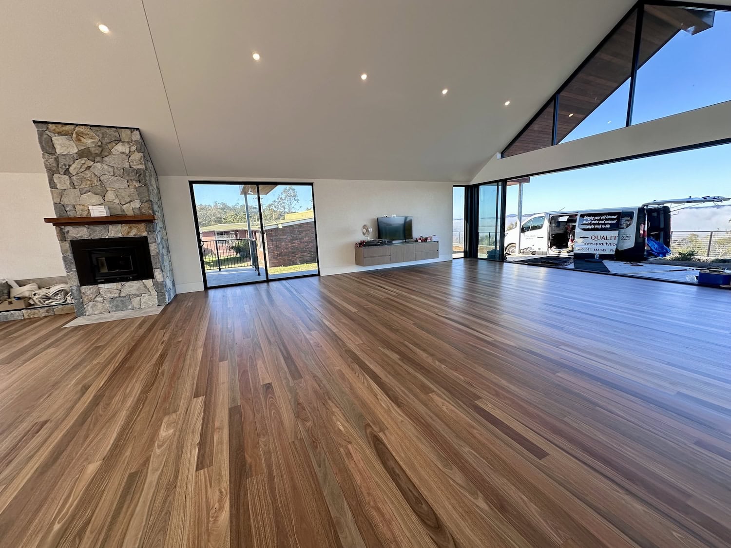 Elegant hardwood flooring in a modern living room with stone fireplace in Hamilton Brisbane