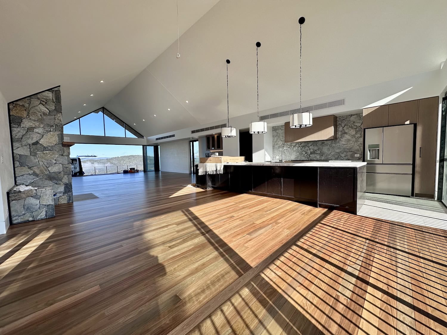Hardwood flooring in modern open-plan living space with large windows — Clayfield floor sanding job
